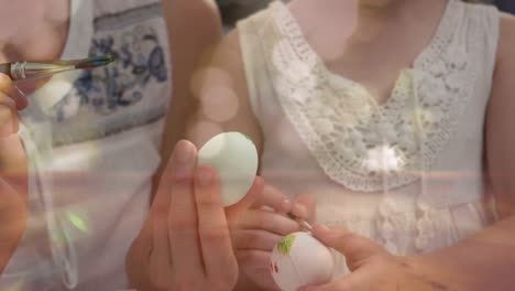 Animation-of-mother-and-daughter-decorating-Easter-eggs-together-with-glowing-spotlights-flickering-