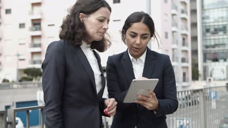 businesswomen using tablet pc on street