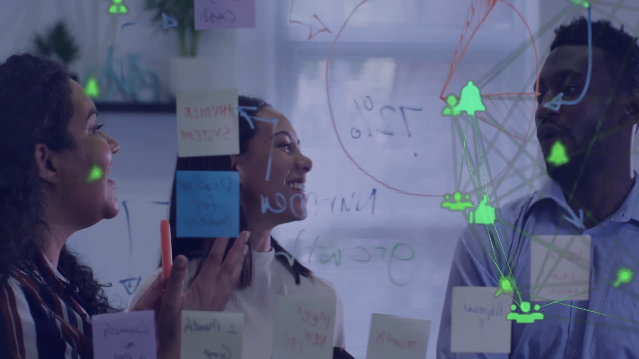 Animation of network of media icons over diverse male and female colleagues brainstorming at office
