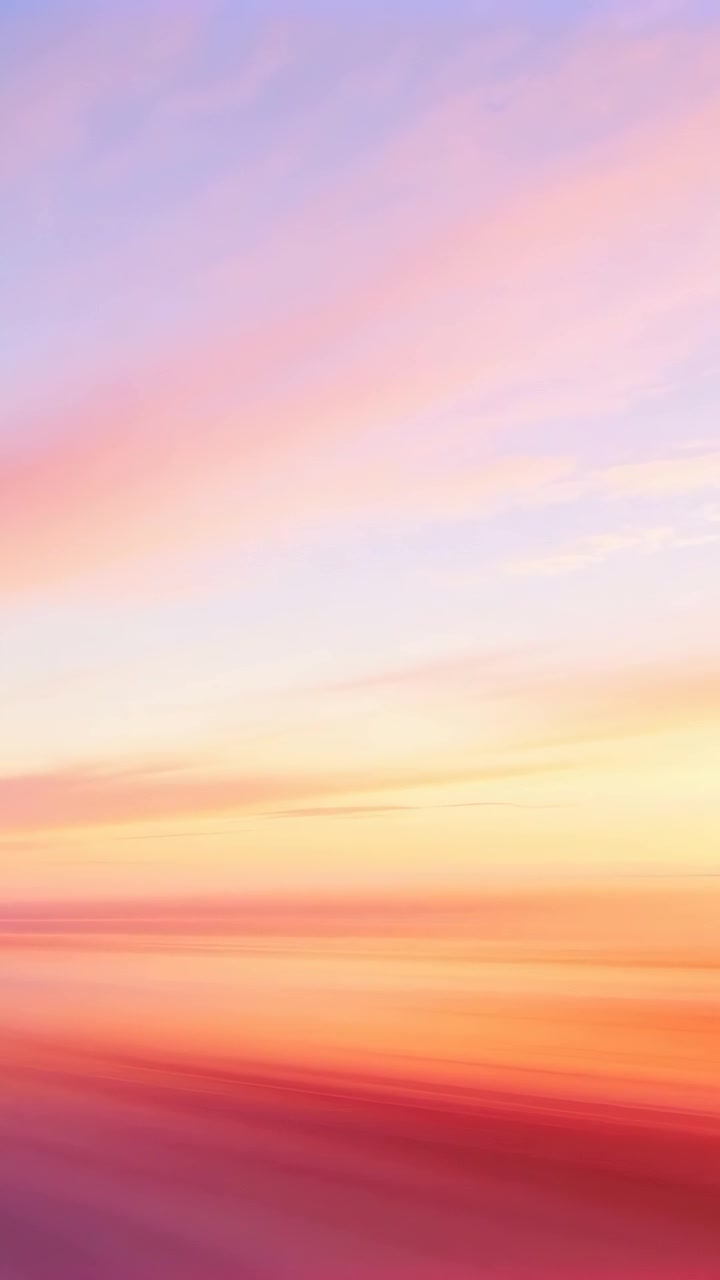 Vertical video: Shifting pastel sky warming coastal horizon at sunrise, showing reflective sea