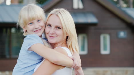 Portrait-Of-A-Mother-With-A-Little-Daughter-Hugging-Against-The-Background-Of-Their-New-Home-Looking