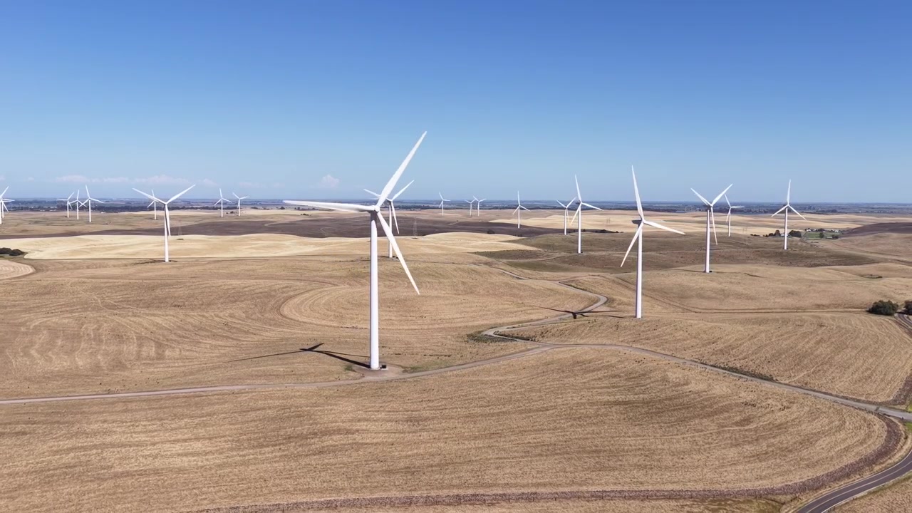 Turbine eoliche che girano in un vasto paesaggio arido a Rio Vista, California, generando energia pulita e rinnovabile sotto un cielo azzurro e limpido, evidenziando l'energia sostenibile e la conservazione ambientale