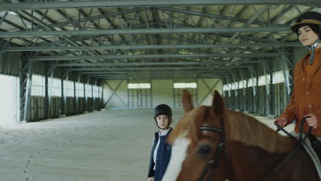 woman riding horse in equestrian school