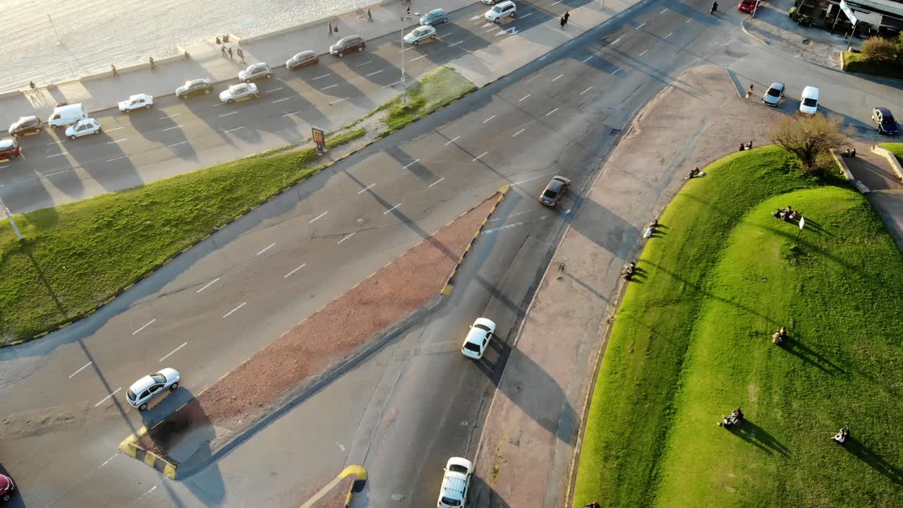 video aéreo de un automóvil blanco en una carretera con tráfico en la costa a través del parque en un día soleado ubicado en montevideo uruguay