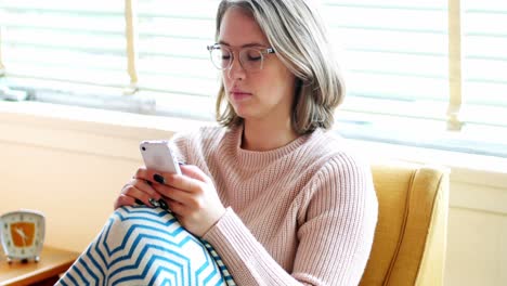 hermosa mujer enviando mensajes de texto en el teléfono móvil en la sala de estar