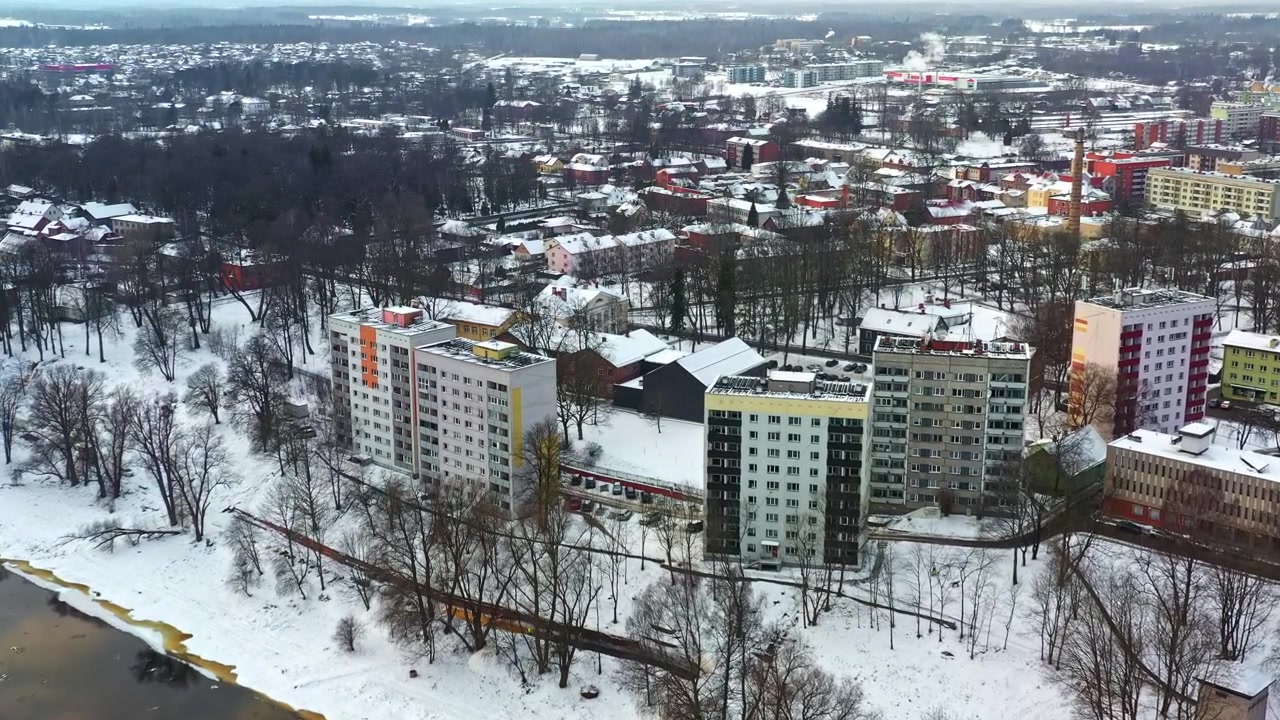 Panoramisk flyfoto av et boligområde i en europeisk by dekket av snø.
