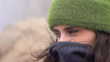 cute woman protecting herself from the wind on a winter cold morning at the mountain