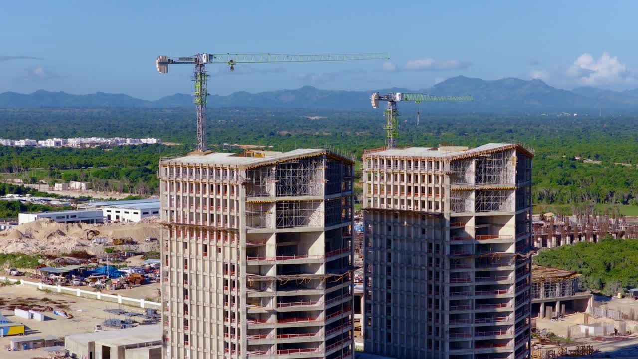 Vista aerea con drone di un cantiere edile di grattacieli a Punta Cana. Gru a torre in cima alle strutture in cemento. Ideale per concetti immobiliari e di sviluppo, Repubblica Dominicana