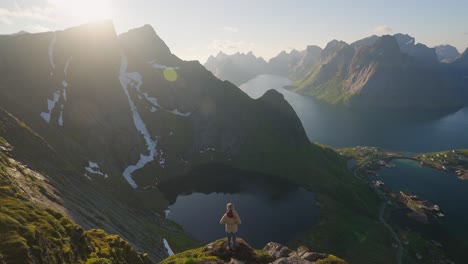 hiker atop reinebringen enjoying breathtaking mountain and fjord views at sunrise