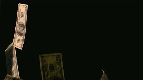 dollar bills rising and falling on black background