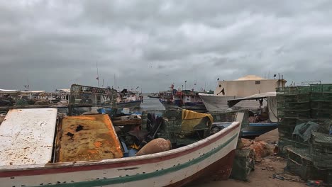 Scenic-view-of-seagulls-flying-over-Djerba-port-with-fishermen-boats,-nets-and-waving-flags-on-cloudy-day,-Tunisia