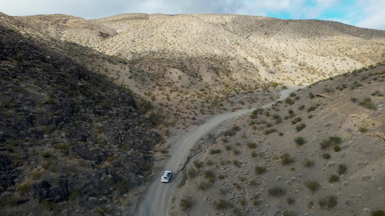 캘리포니아의 식물과 함께 사막 언덕에서 운전하는 색 자동차 뒤의 전망