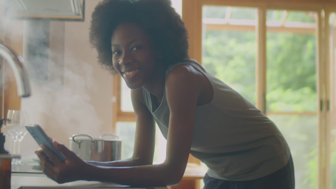 Portrait of Cheerful Black Woman with Phone in Kitchen