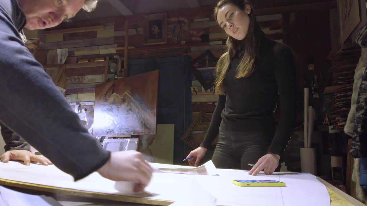 Man helping a woman sketching on a canvas at an art gallery workshop