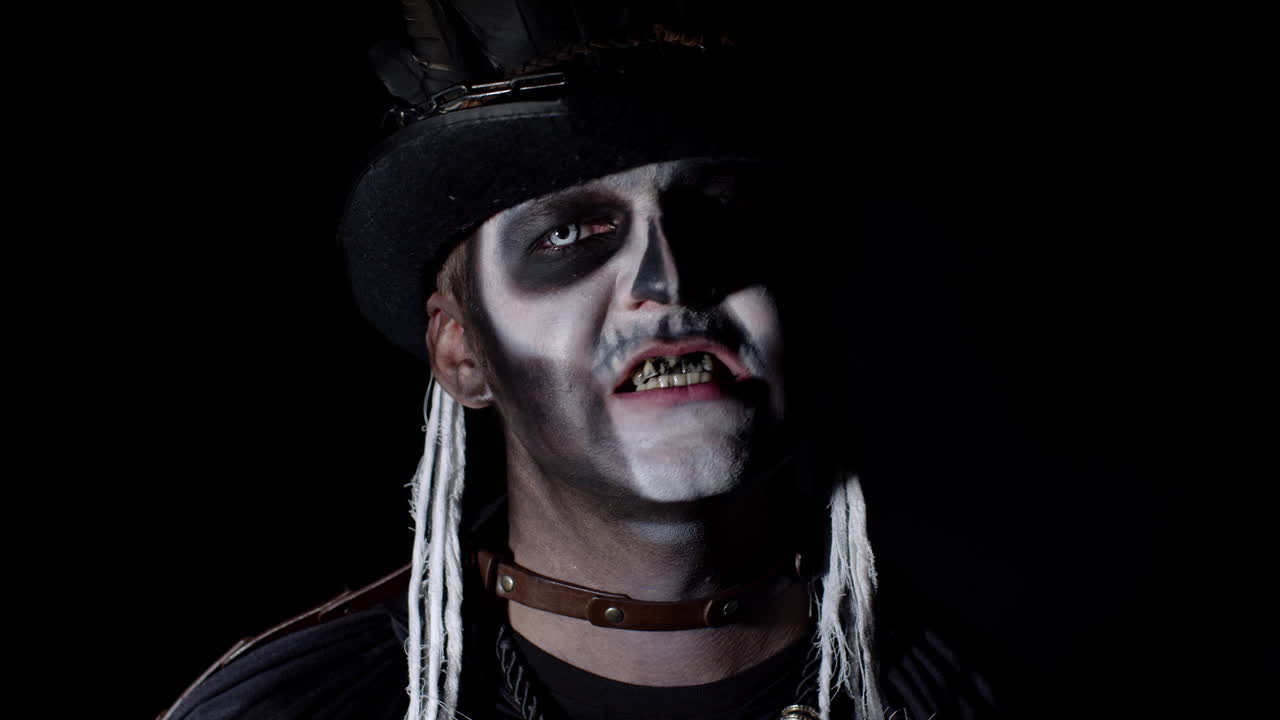 hombre aterrador en esqueleto disfraz de halloween que aparece de la oscuridad cuando la luz cae sobre él