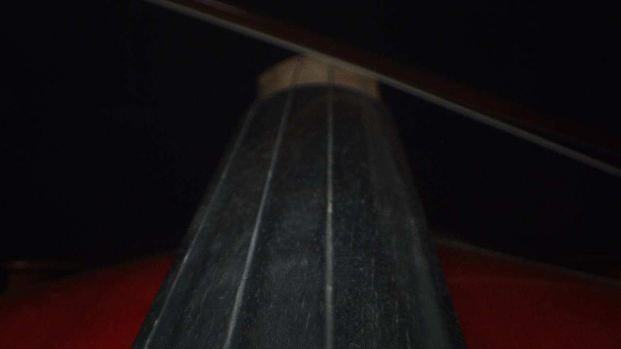 macro artístico en cámara lenta del maestro artesano luthier tocando con un arco en un violín o violonchelo hecho a mano.