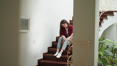 una mujer joven sentada en las escaleras, mirando hacia abajo.