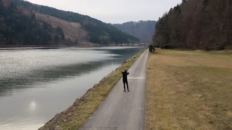 Una-Vista-Alta-De-Un-Joven-Con-Un-Traje-Deportivo-Negro-Ajustando-Su-Capucha-Después-De-Un-Breve-Descanso