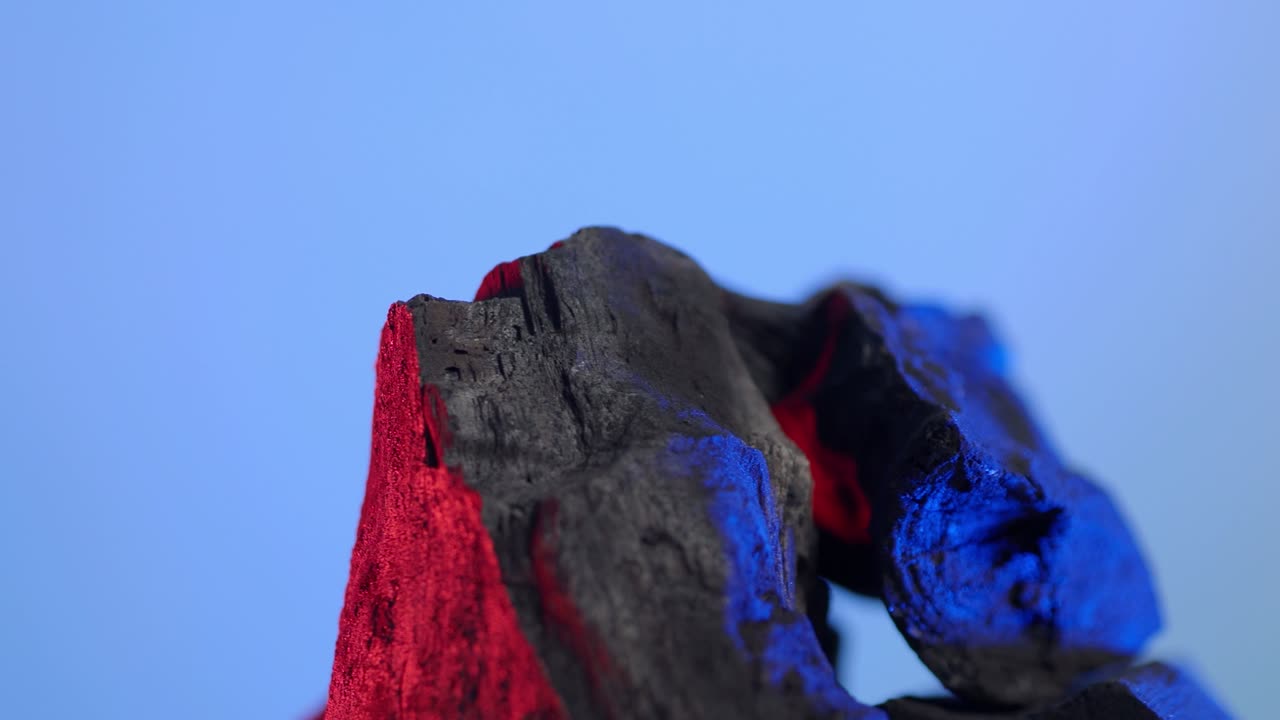 carbón de madera. madera natural o carbón negro tradicional en bucle en giratorio. fondo de pantalla azul o verde con luz led de color. disparo en estática. carbón para cocinar en la parrilla de la barbacoa. carbón negro.