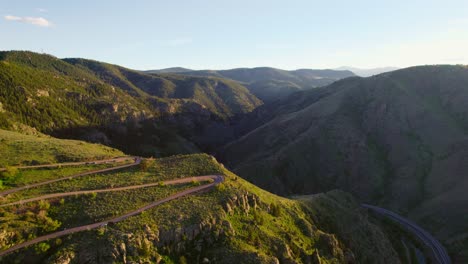 Imágenes-De-Drones-De-Un-Camino-Sinuoso-En-La-Montaña-Durante-La-Hermosa-Puesta-De-Sol-De-La-Hora-Dorada