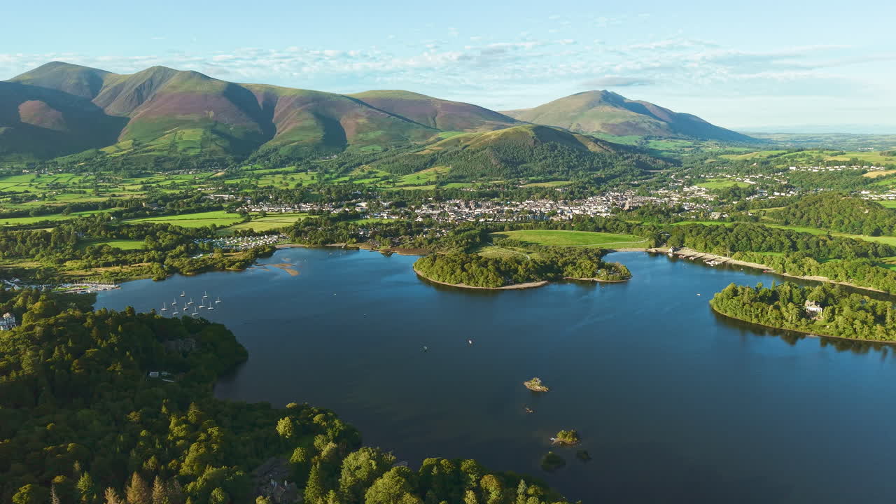 Scenic landscape of the Lake District fells, lake, Keswick, and town during golden hour