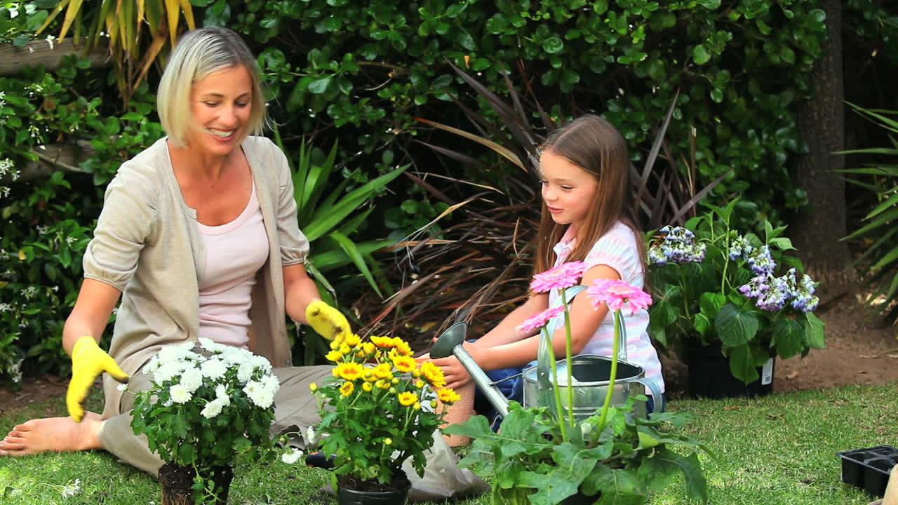 Niña y madre plantando flores en macetas en el jardín