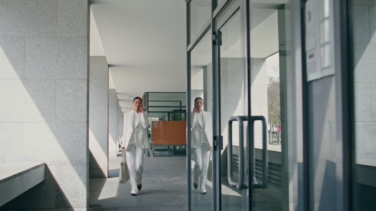 загруженный исполнительный менеджер идет по офисному зданию, разговаривает по телефону.