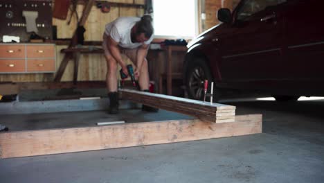 tablas de madera en una abrazadera siendo perforadas juntas por un carpintero