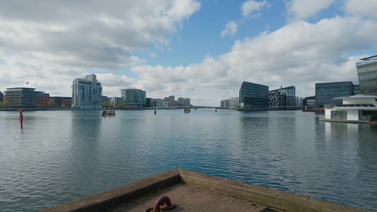 Grattacieli urbani in cemento lungo il fiume, ripresa con stabilizzatore gimbal. Inquadratura ampia con avvicinamento a 60fps, camminando in avanti sul lungomare di Copenaghen in Danimarca, Scandinavia.