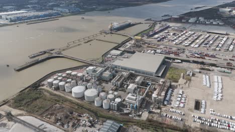 aerial perspective of riverside oil storage facility with orderly cylinders, pipelines and service roads illustrating large-scale fuel logistics and energy distribution operations