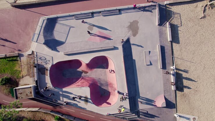 Vista drone di adolescenti nello skatepark che giocano su struttura in cemento con atmosfera vintage