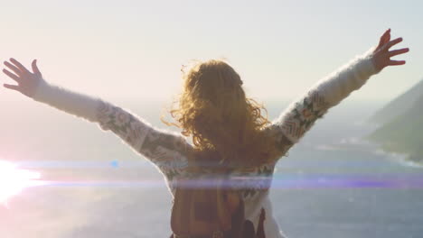 animation of light trails over caucasian woman with arms outstretched on beach