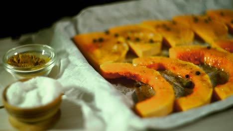 Raw-pumpkin-slices-pouring-salt.-Baked-vegetables-cooking.-Raw-pumpkin-baking