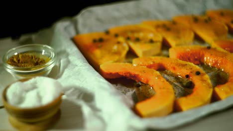 raw pumpkin slices pouring salt. baked vegetables cooking. raw pumpkin baking