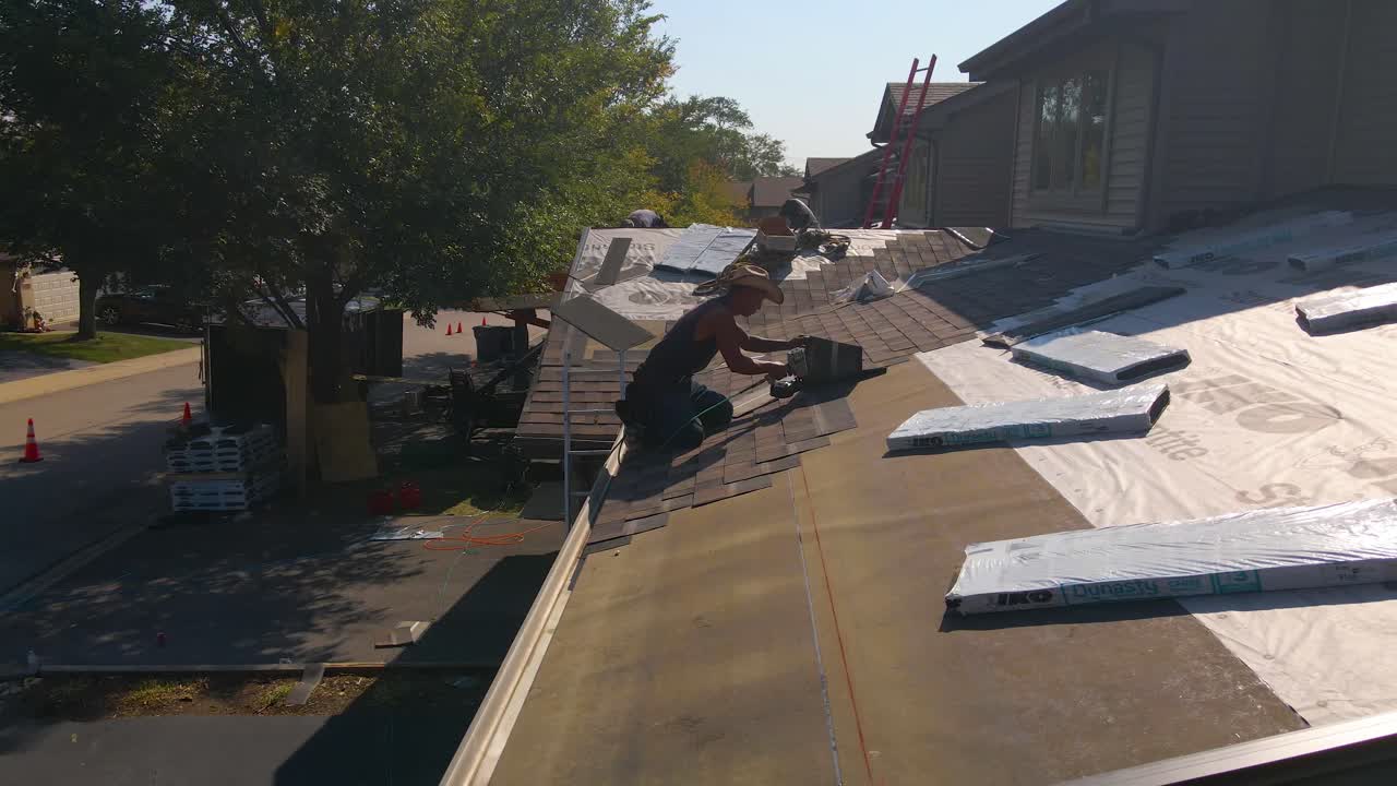 Hispanic construction workers laboring on top of a roof on a bright sunny day, the blue collar workers are diligent and using great technical skills