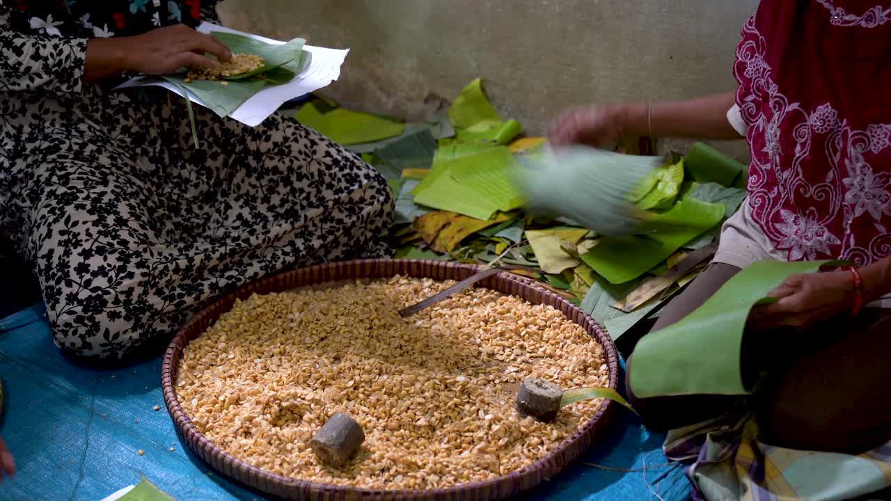 mujeres empacando soja en hojas de plátano, preparación tradicional javanesa de tempeh
