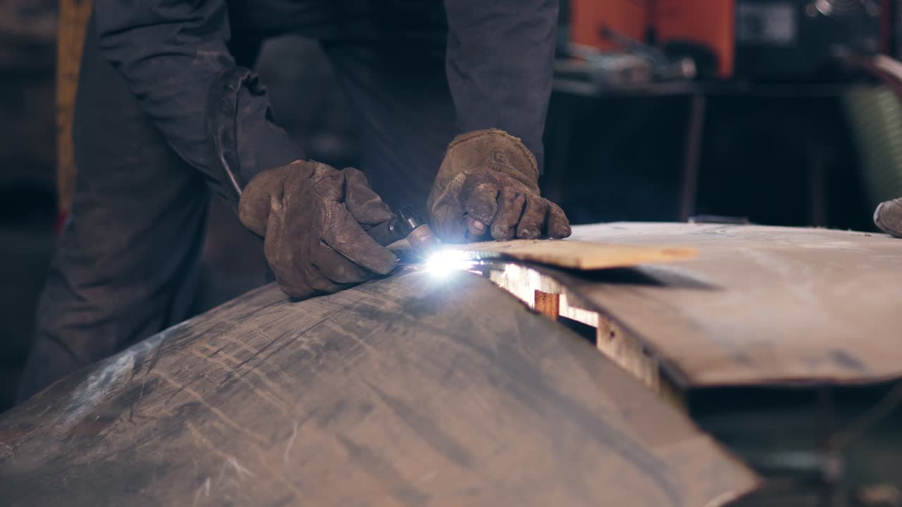 Workman's hands cutting metal with torch using wood plank to adjust and even line