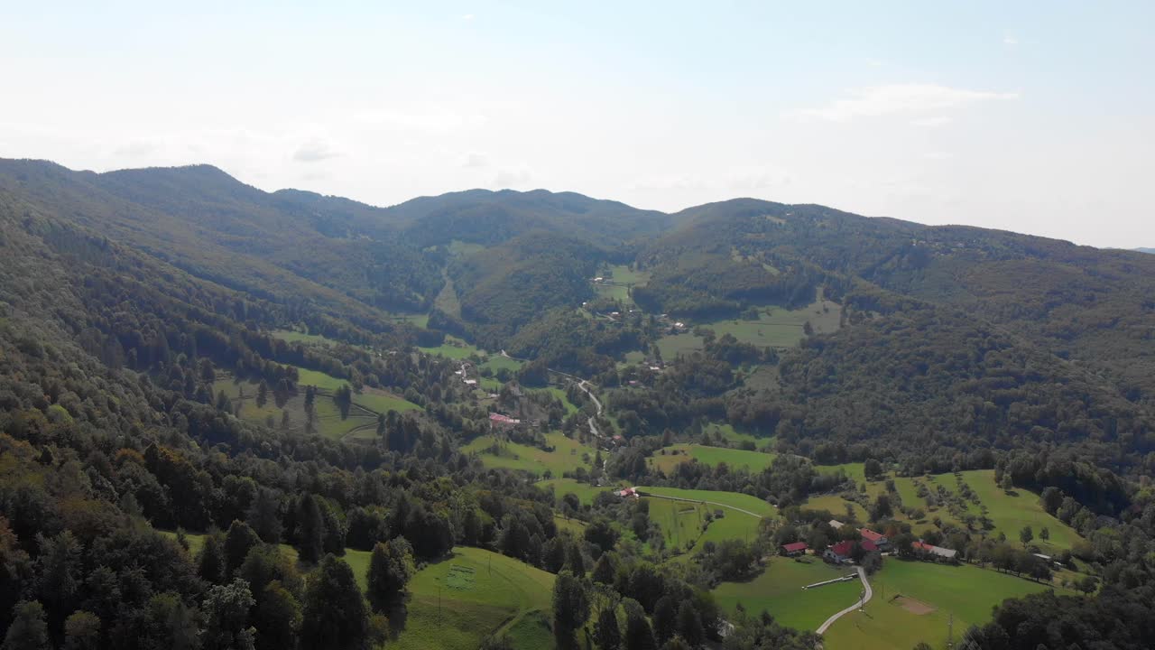 vista aérea de colinas verdes onduladas con un gran bosque en las zonas rurales de eslovenia, nublado