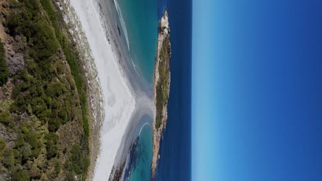 vertical drone backwards shot of diamond island with sandy beach on coastline of tasmania in summer