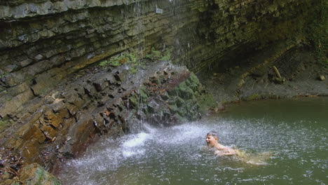 man swimming in a waterfall