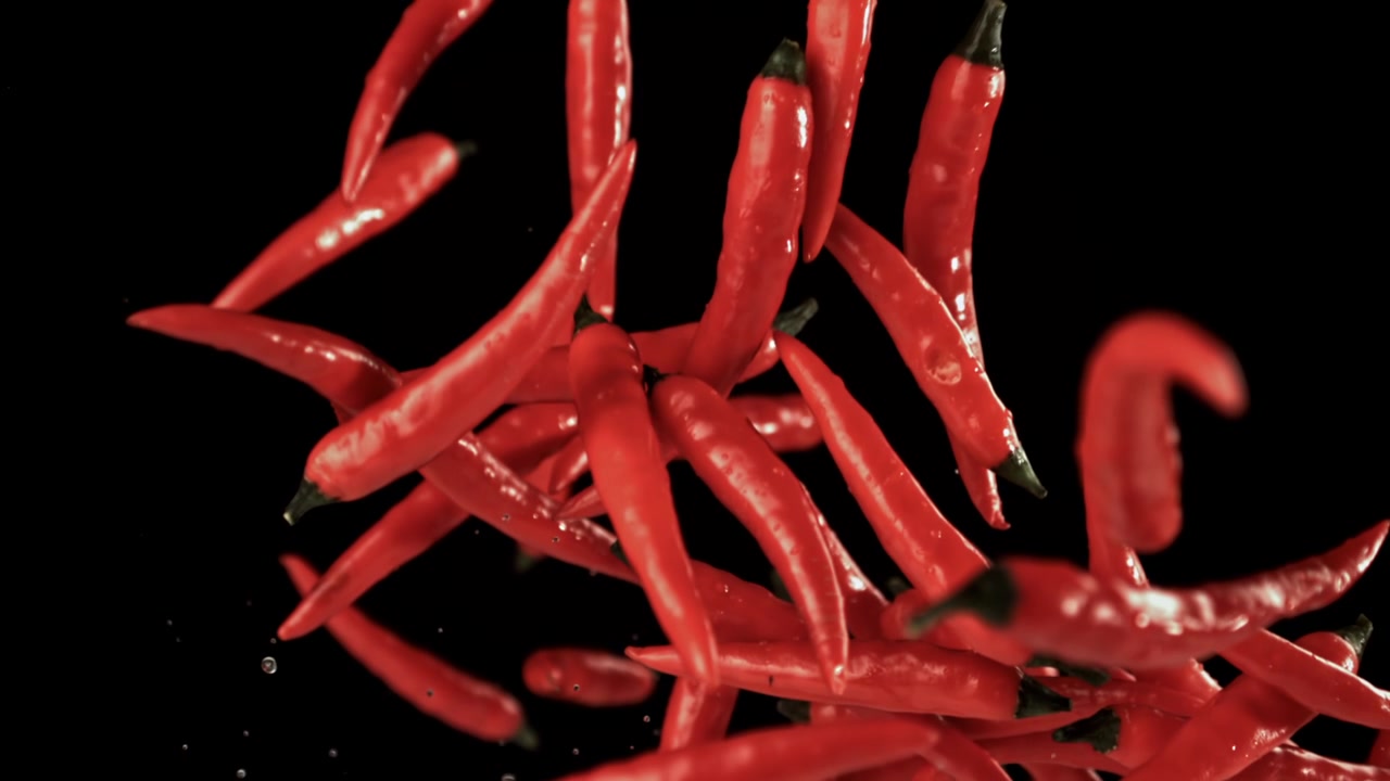 Fresh Red Chili Peppers Falling in Slow Motion on Black Background