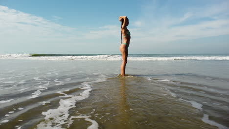 Fit-tanned-beauty-posing-on-sandy-Vietnam-ocean-coastline,-orbit-view