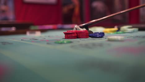 un crupier está manejando las fichas en una mesa de ruleta con su rastrillo mientras la rueda gira-1