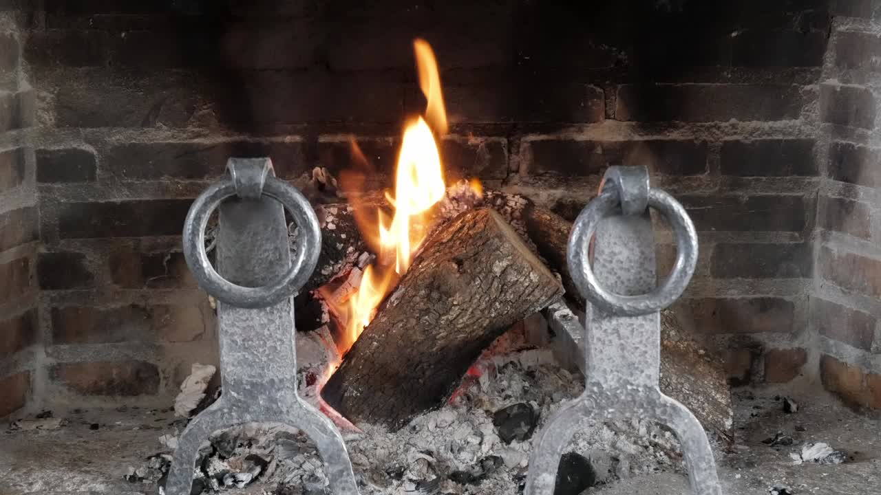 Fire burning in a cozy fireplace with logs crackling and glowing embers
