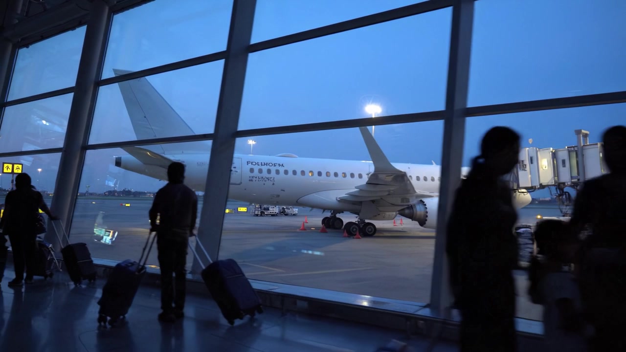 Passagerer i lufthavnen venter på boarding, mens flyet gøres klar til en problemfri afgang på en klar aften med blød belysning og travlt jordpersonale