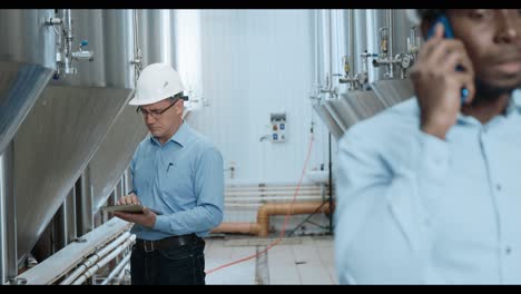 industrial workers inspecting brewery tanks