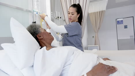 Diverse-female-doctor-talking-with-senior-female-patient-in-hospital-room,-slow-motion