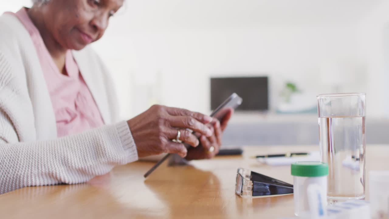 Portrait of senior african american woman sitting at table, using tablet