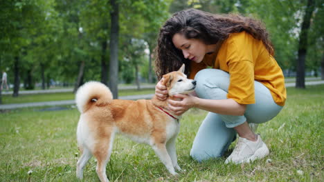 woman kissing her shiba inu dog in a park