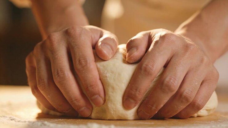 Thumbs pressing, hands folding and pinching dough on counter in kitchen, shaping ball for baking